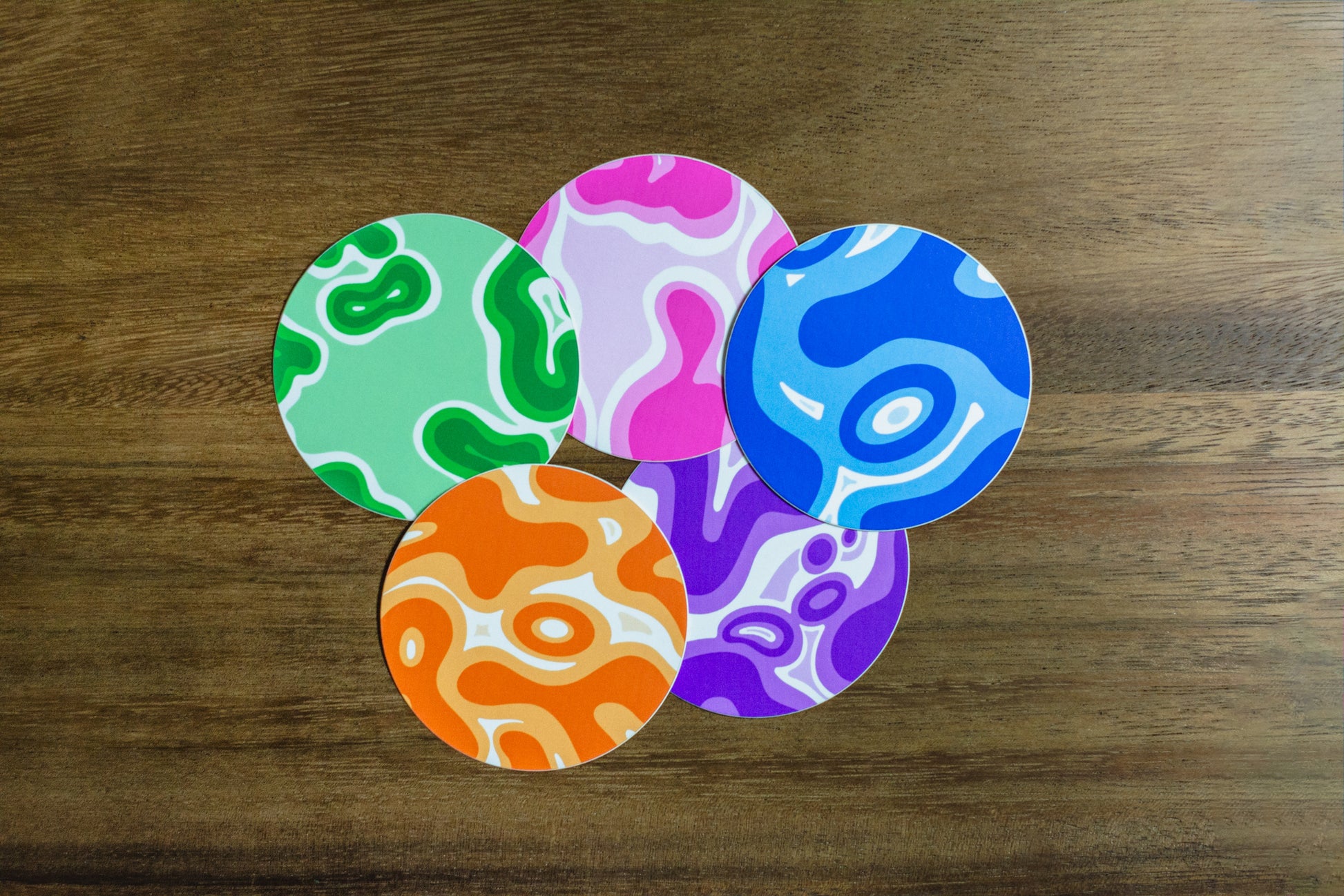 Five colorful 3” round stickers with abstract design on wood surface