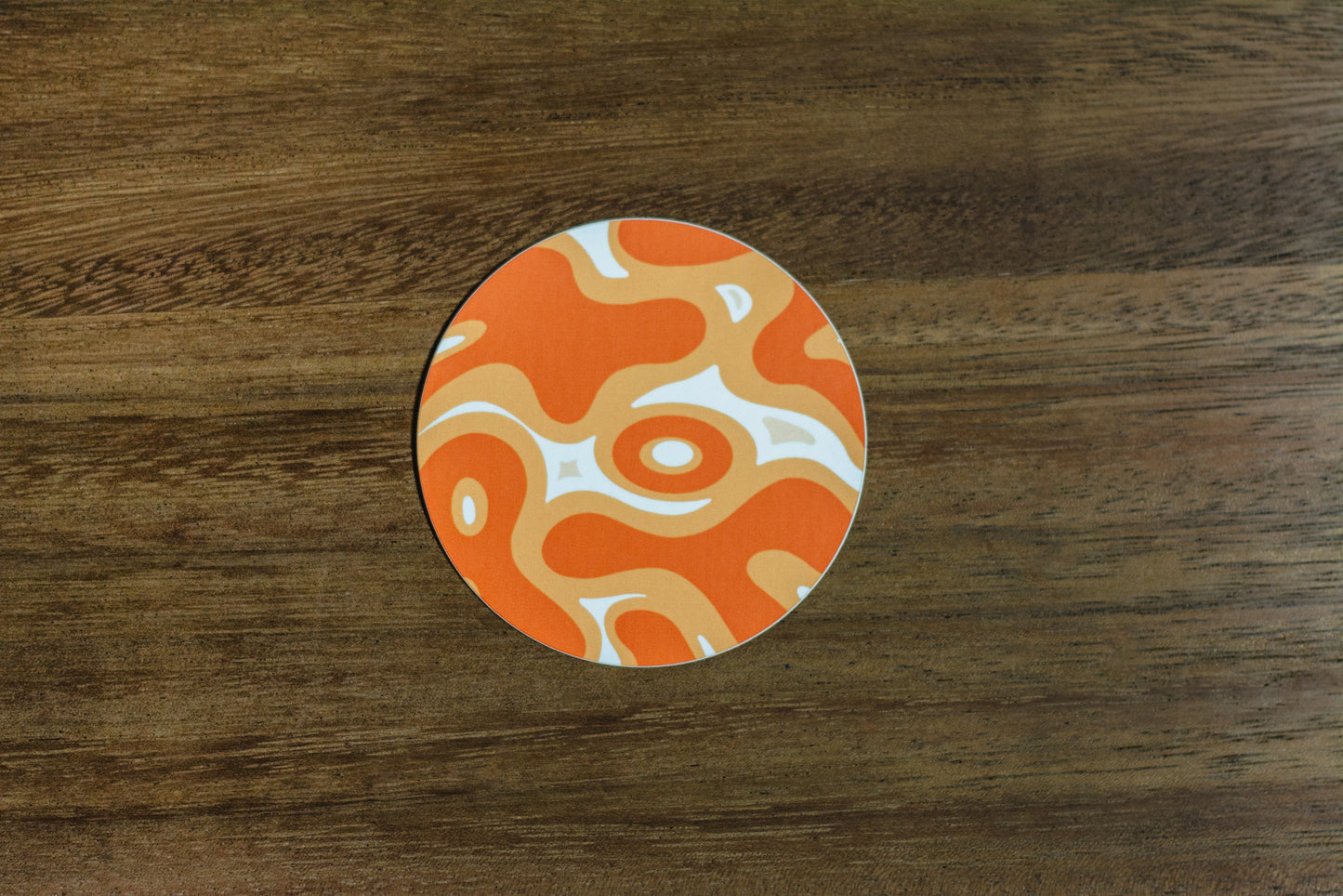 Orange abstract 3” sticker on wood surface