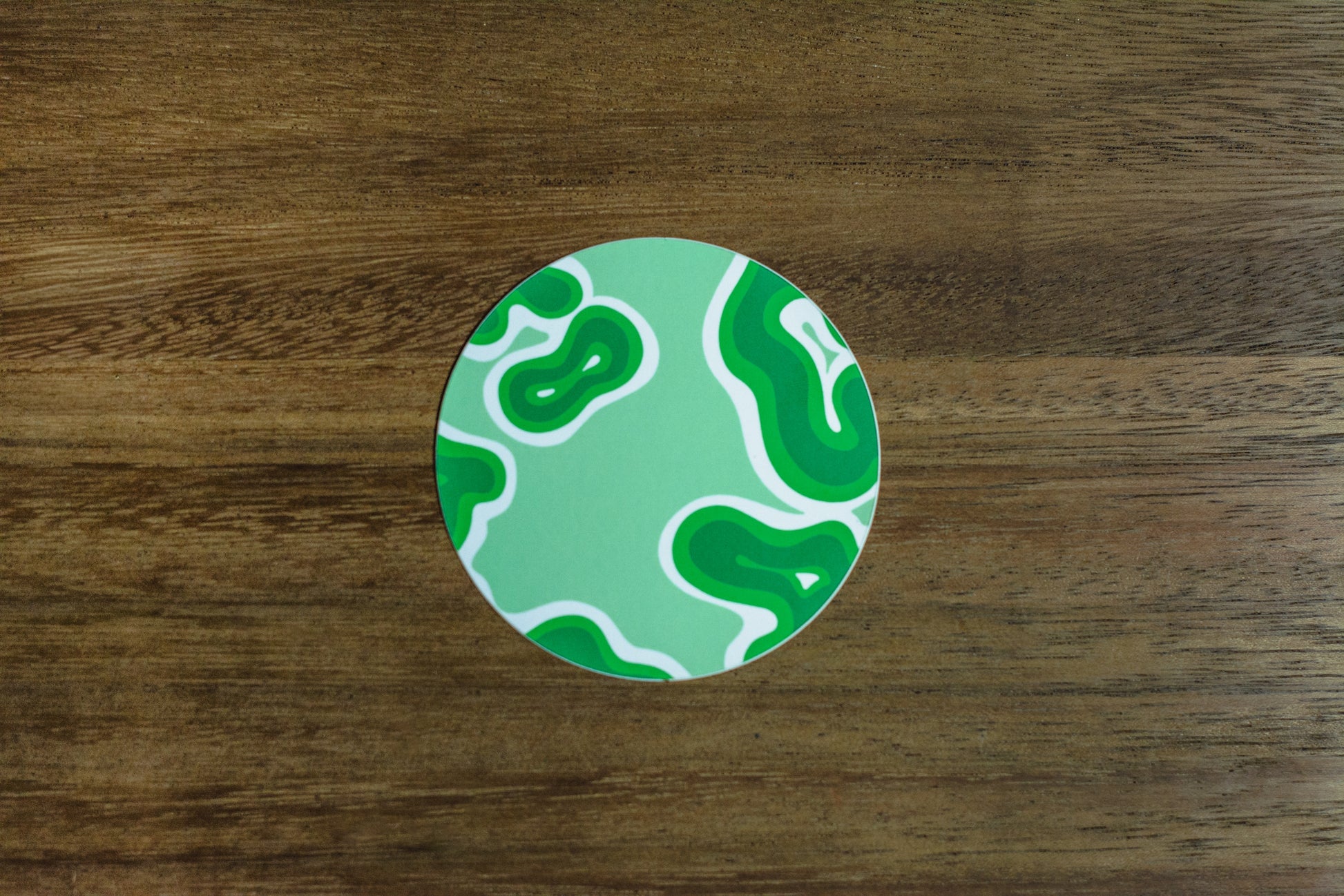 Green abstract 3” sticker on wood surface